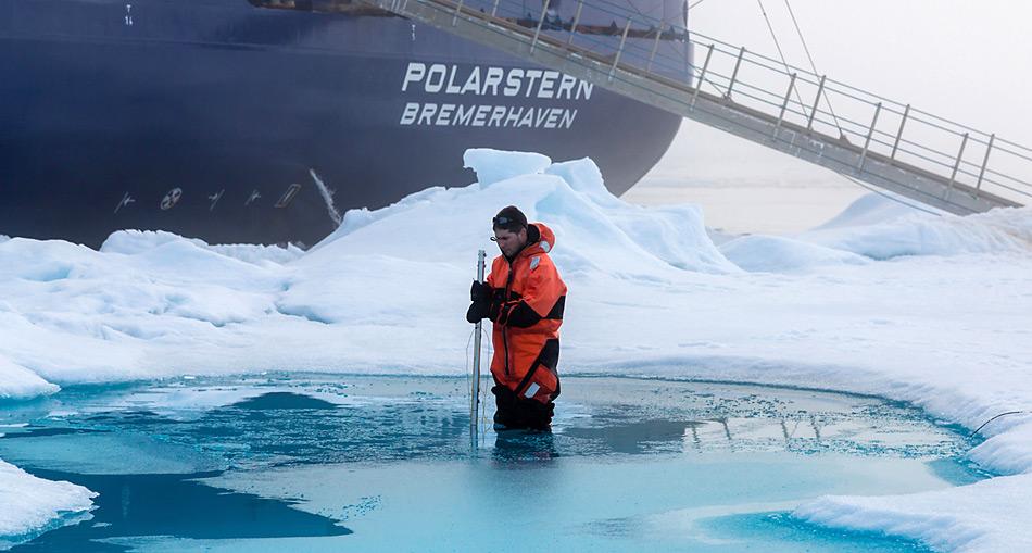 Der Meereisphysiker Dr. Marcel Nicolaus vermisst während der Polarstern-Expedition ARK-XXVII-3 auf einer Eisscholle die Tiefe eines Schmelzwassertümpels. Foto: Stefan Hendricks, AWI